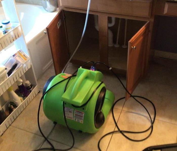 a green air mover placed near the underneath of a sink